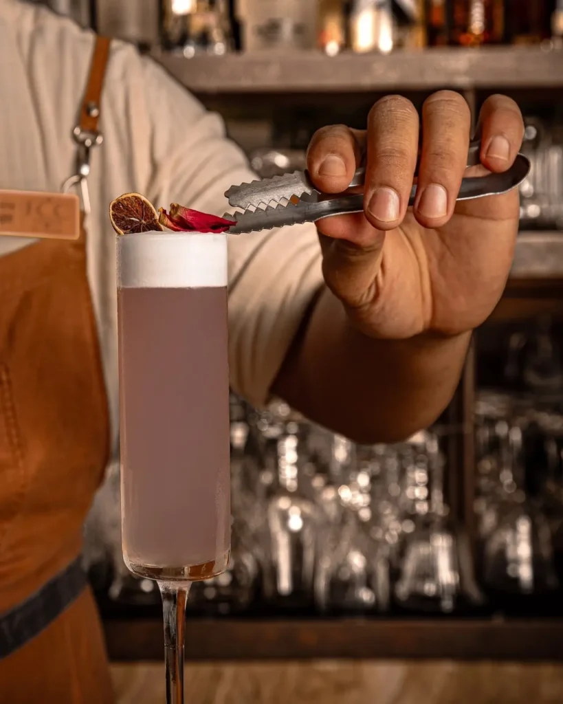 Apsara Sour cocktail finished with foam, dried citrus and rose petals at the bar.