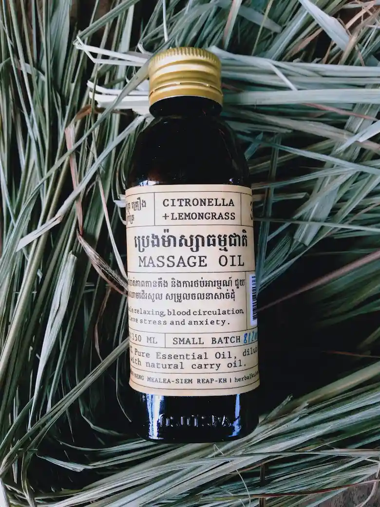 Bottle of Herbal Kulen citronella and lemongrass massage oil displayed on dried botanical leaves.