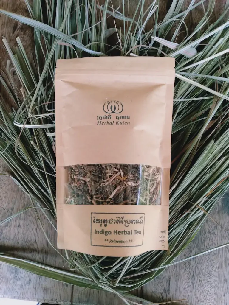 Herbal Kulen Indigo Herbal Tea pouch displayed on dried lemongrass leaves.