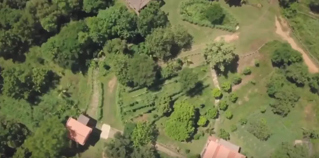 Aerial view of the Herbal Kulen botanical farm in Cambodia, showing cultivated garden plots, trees and farm buildings.