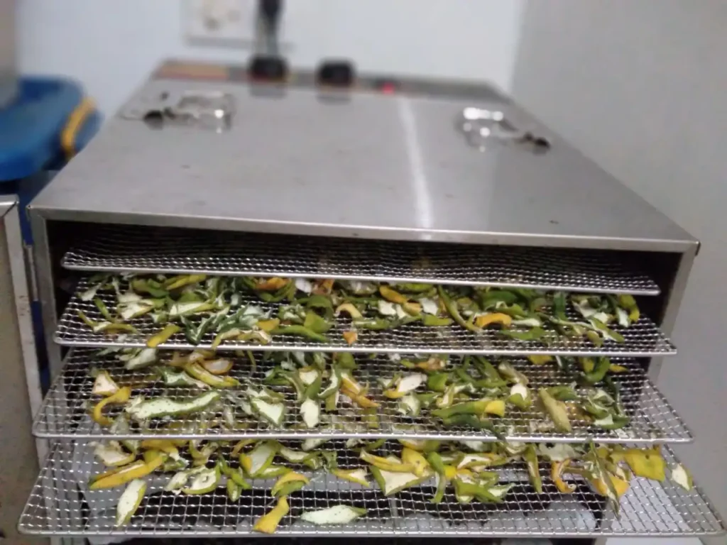 Bitter orange peels drying on metal trays during the Herbal Kulen botanical preparation process.
